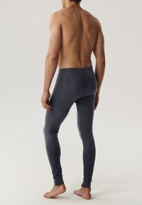Dopasowane ciemnoszare legginsy z gładkiego materiału, z delikatną prążkowaną strukturą na mankietach kostek i bezszwowym pasem w talii.