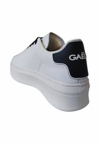 Sneaker bianca con tomaia in pelle liscia, accento nero sul tallone e suola spessa bianca. "GAËLLE" è impresso sul retro.