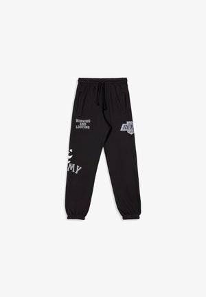 Zwart trainingsbroek met een elastische tailleband, zijzakken en enkelmanchetten. Bevat witte tekst en graphics, waaronder "BURNING AND LOOTING."