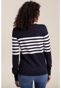 Marineblauer Pullover mit weißen horizontalen Streifen auf dem oberen Rücken und an den Ärmeln. Gerippte Bündchen und Saum. Weiche, gestrickte Textur. Figurbetonte Form.
