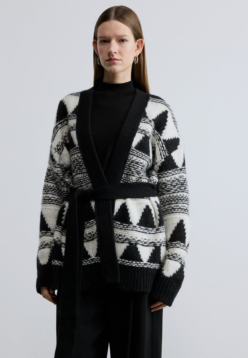 Ανοιχτό μαύρο και άσπρο ζακέτα με γεωμετρικά σχέδια, ριμπ μανσέτες και ζώνη στη μέση, κατασκευασμένη από υφή πλεκτό υλικό.