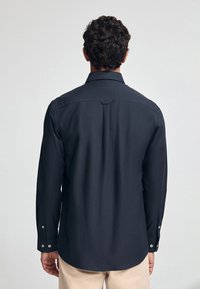 Dunkelblaues Langarmshirt mit Kragen, geradem Rückenpasse und knöpfbaren Manschetten. Glattes Material mit taillierter Passform.