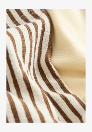 Detailný záber na mäkkú látku s textúrovanými hnedými a krémovými pruhmi vedľa hladkej béžovej látky, zobrazujúci záhyby a tkané vzory.