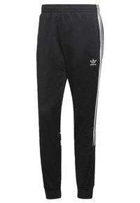 Pantaloni sportivi neri con vita elasticizzata, tre strisce bianche sui lati e logo adidas sulla coscia sinistra.