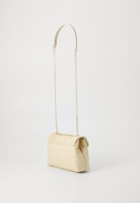 Šviesiai rudos spalvos audinė rankinė su struktūrizuotu dizainu, pasižyminti auksinės spalvos grandinėlės petneša ir sulankstomu viršutiniu dangteliu, kuris atskleidžia tekstūruotą paviršių.