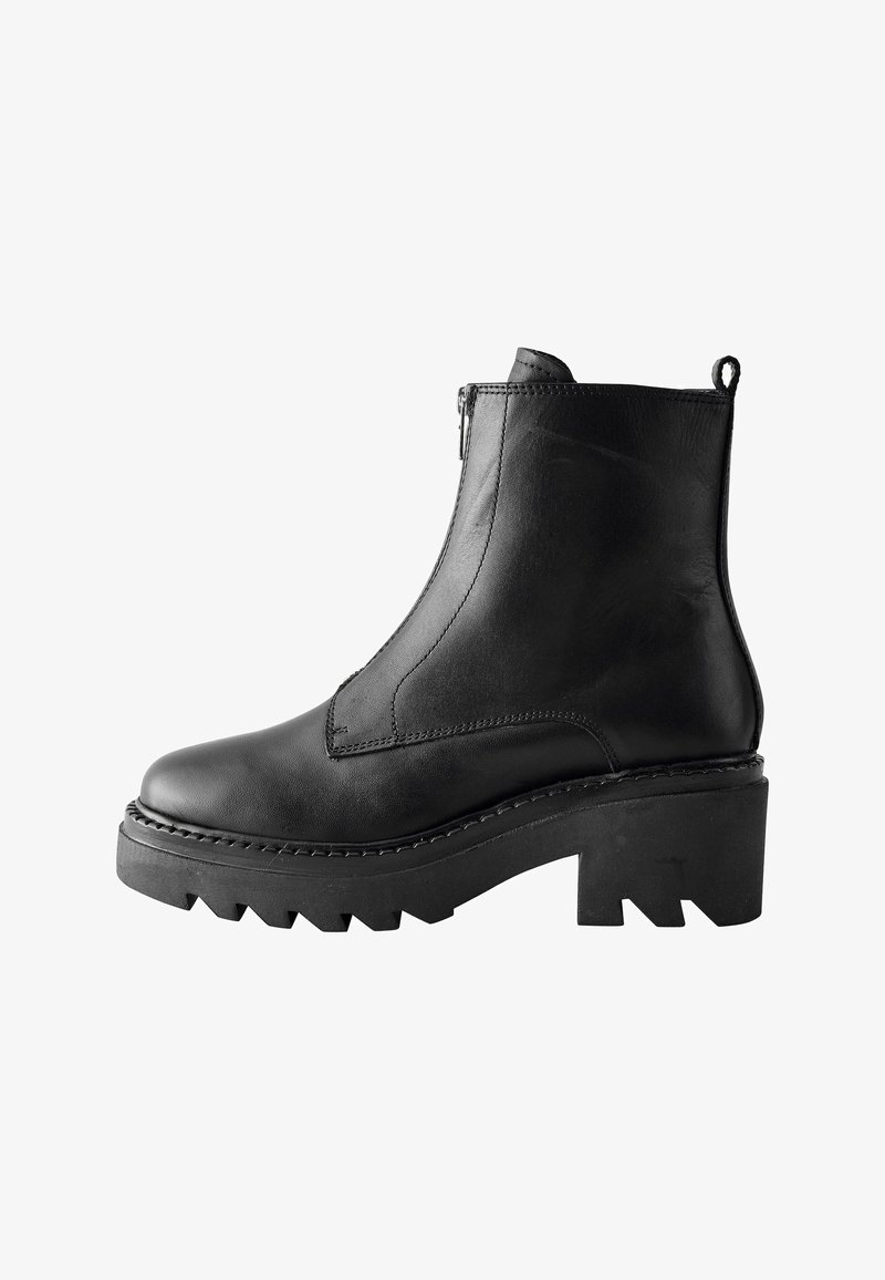 Bottine en cuir noir avec une fermeture éclair sur le côté, design texturé, semelle plateforme épaisse et motif de crampons prononcé. Dispose d'une languette à l'arrière.