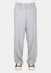 Pantaloni in lino grigi con una vestibilità ampia, presenti di chiusura frontale con bottone, pieghe e tasche. Abbinati a sneakers di colore chiaro.