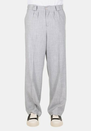 Pantaloni in lino grigi con una vestibilità ampia, presenti di chiusura frontale con bottone, pieghe e tasche. Abbinati a sneakers di colore chiaro.