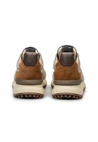 Par de zapatillas de ante beige y marrón vistas desde atrás, con suelas gruesas beige y textura marrón antideslizante, y lengüetas negras en el talón con texto.