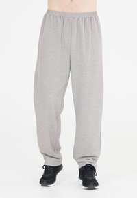 Graue, leichte Jogginghose mit einem elastischen Bund, schmal zulaufenden Beinen und einer weichen Textur, kombiniert mit schwarzen Sportschuhen.