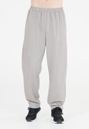 Grijze, lichte trainingsbroek met een elastische tailleband, taps toelopende pijpen en een zachte textuur, gecombineerd met zwarte sportschoenen.