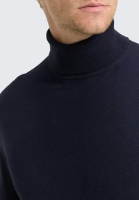 Marineblauer Rollkragenpullover aus weichem, gestricktem Material. Hat ein enganliegendes Design und einen gerippten Ausschnitt für zusätzliche Textur und Struktur.