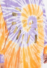 Felpa tie-dye in arancione e viola con accenti dorati. Vestibilità ampia, maniche lunghe, caratterizzata da un motivo a raggiera creato dalla tintura.