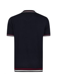Marineblaues Poloshirt aus strukturierter Baumwolle, mit klassischem Kragen und kontrastierenden gestreiften Akzenten in Rot und Weiß an den Ärmelbündchen und am Saum.