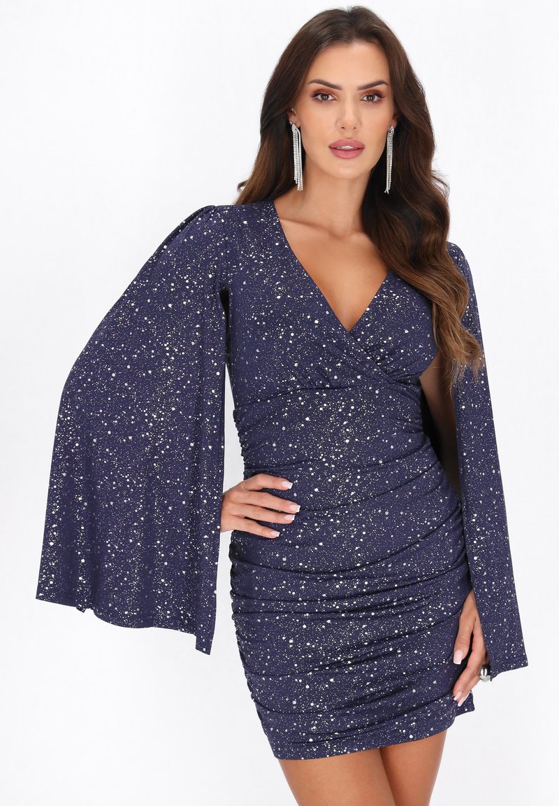 Dunkelblaues Kleid mit V-Ausschnitt und Glockenärmeln, das einen gerafften Körper und metallische Sprenkel im Stoff aufweist.