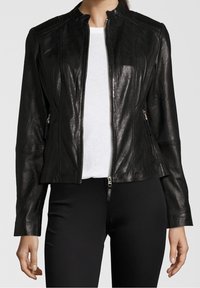 Sort læderjakke med rillede skulderdetaljer, front lynlås lukning og to lynlåslommer på siden. Båret over en hvid skjorte.