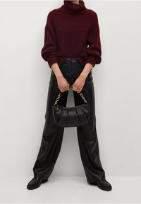 Burgundinvärinen neulottu pooloneule, väljä ja kuvioitu; mustat leveälahkeiset nahkahousut; musta käsilaukku ketjullisella kahvalla.