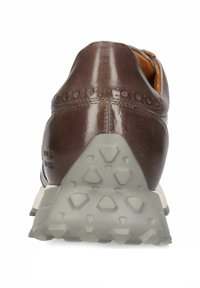 Brun lädersko med en slät yta, prydd med dekorativa perforeringar, en tanfärgad insida och en strukturerad grå gummisula.