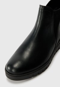 Schwarze Leder-Ankle-Boots mit glatter Oberfläche, elastischen seitlichen Einsätzen, runder Zehenform und strukturiertem Gummisohle mit Zickzackmuster.
