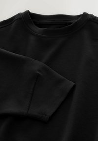 Schwarzer Sweatshirt mit rundem Halsausschnitt, langen Ärmeln mit umgeschlagenen Bündchen und glatter Textur mit minimalen Nähten.