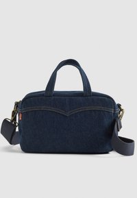 Bolso de denim, azul oscuro con dos asas cortas y una correa desmontable. Presenta costuras en contraste y un diseño curvado en la parte frontal.