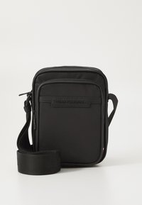 Geantă de umăr din nailon negru, cu curea ajustabilă, închidere cu fermoar și logo-ul mărcii gravat. Formă rectangulară cu textură netedă.
