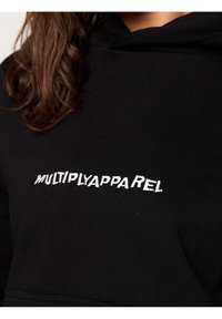 Felpa nera con cappuccio realizzata in morbido materiale, con la scritta "MULTIPLYAPPAREL" ricamata in bianco sul petto. Design e texture minimalisti.