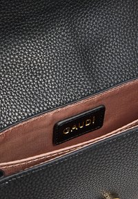 Borsa a mano in pelle nera testurizzata con fodera interna liscia di colore rosa chiaro, con un'etichetta nera recante la scritta "GAUDI" in oro.