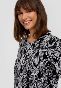 Zwart-wit patroon top met een textuurstof, featuring een paisley ontwerp en een ronde halslijn. Korte mouwen, geribbelde stof.