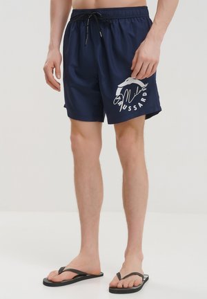 Costumi da bagno blu navy con vita elasticizzata e cordino. Presentano una grafica bianca sulla gamba sinistra. Realizzati in tessuto leggero.