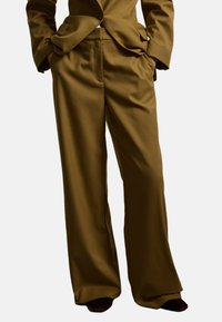 Pantaloni a gamba larga in un ricco tessuto marrone, caratterizzati da una superficie liscia, tasche frontali e una vestibilità pulita e sartoriale.