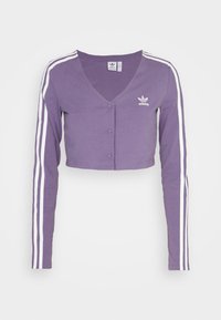 Lila kortad cardigan med långärmar, V-halsringning och vita sidremsor. Har Adidas-logga på vänster bröst, tillverkad av mjukt tyg.
