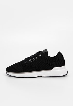 Baskets noires à lacets avec tige en tissu texturé, semelle blanche et logo « GANT » sur le côté et la languette.