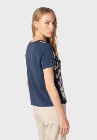 Camiseta de algodón de color navy con mangas cortas, con un ligero patrón abstracto en el frontal, fabricada en material suave y con un corte relajado.