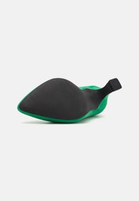 Scarpa con tacco alto in suede verde, punta affusolata, suola in gomma nera liscia e cinturino posteriore per supporto.