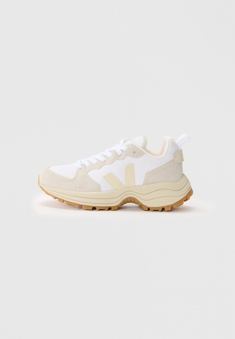 White and beige sneaker with mesh upper, suede accents, and textured rubber sole. Features a rear tab and stylized side logo.