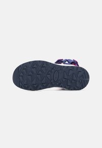 Sole sandálu s geometrickým vzorem v tmavě modré, fialové a růžové barvě, s nastavitelnými pásky viditelnými nad podrážkou na bílém pozadí.