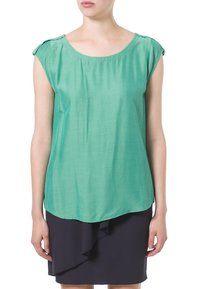 Zelený krátký rukáv top z lehkého materiálu, s uvolněným střihem a kulatým výstřihem. Nosený s tmavou volánkovou sukní.
