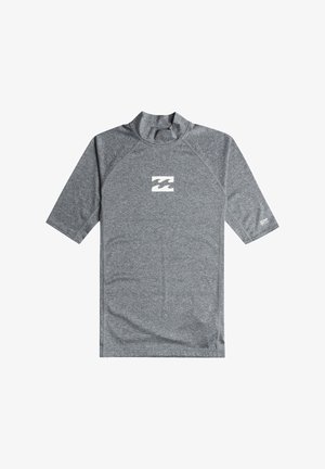 Szary rash guard z krótkim rękawem z małym białym logo fali na piersi i etykietą ochrony UV na lewym rękawie.