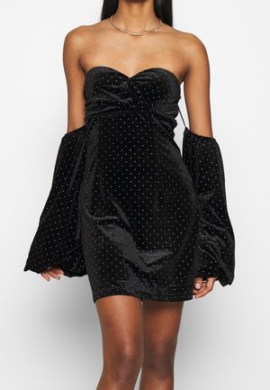 Schulterfreies schwarzes Samt-Minikleid mit silbernen Strasssteinen und abnehmbaren langen, aufgeblasenen Ärmeln, getragen von einer Person mit mittlerer brauner Haut.