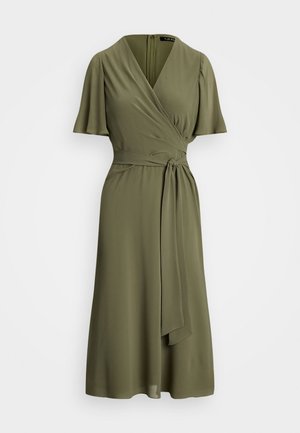 Oliwkowa sukienka kopertowa z krótkimi, rozkloszowanymi rękawami. Zawiera pasek w talii i dekolt w szpic. Gładki materiał z płynącą sylwetką.