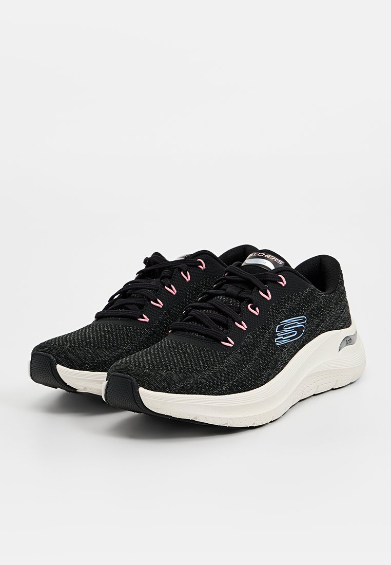 Zapatos atléticos negros con parte superior de punto texturizado, acentos en rosa, punta redondeada y detalle del logo en el costado. Suela acolchada para mayor comodidad.