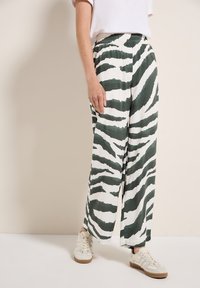 Groen en wit gestreepte wijde broek van een lichtgewicht materiaal, met een elastische tailleband en gecombineerd met witte sneakers.