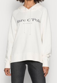 Felpa crema con tasca frontale a marsupio, cordini e stampa del logo in blu scuro. Presenta maniche lunghe e una vestibilità comoda.