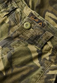 Camo-mønstrede shorts i khaki- og grønne nuancer, med et mærketikett, knaplukning og detaljeret syning.