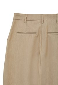 Pantaloni beige in un tessuto liscio e testurizzato. Caratteristiche includono una cintura piatta, due tasche posteriori con aperture a filetto e cuciture sottili.