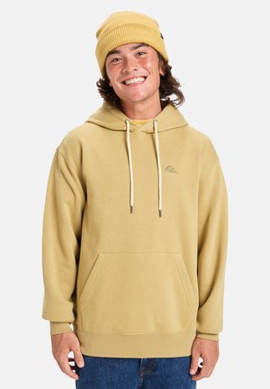 Khaki hoodie with a front pocket, drawstring hood, and a small logo on the chest. Paired with a ribbed yellow beanie.