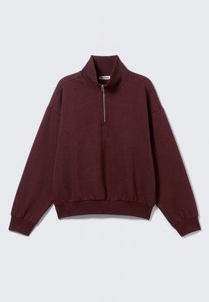 Bordeauxroter Sweatshirt mit Viertel-Reißverschluss aus weichem Stoff, mit Stehkragen und gerippten Bündchen, locker geschnitten und mit angesetzten Schultern.