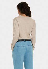 Beige knit pullover with puffed sleeves and a rounded neckline, paired with light blue wide-leg jeans featuring a black belt and back pockets.