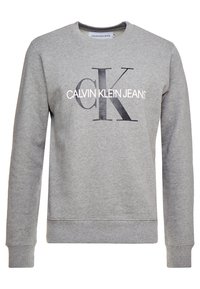 Šedá mikina s dlouhým rukávem a kulatým výstřihem, na přední straně potisk s logem "CK" a "Calvin Klein Jeans" v černé a bílé barvě.